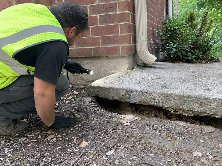 Inspecting settled concrete that has dropped beside a foundation in Columbia, MD